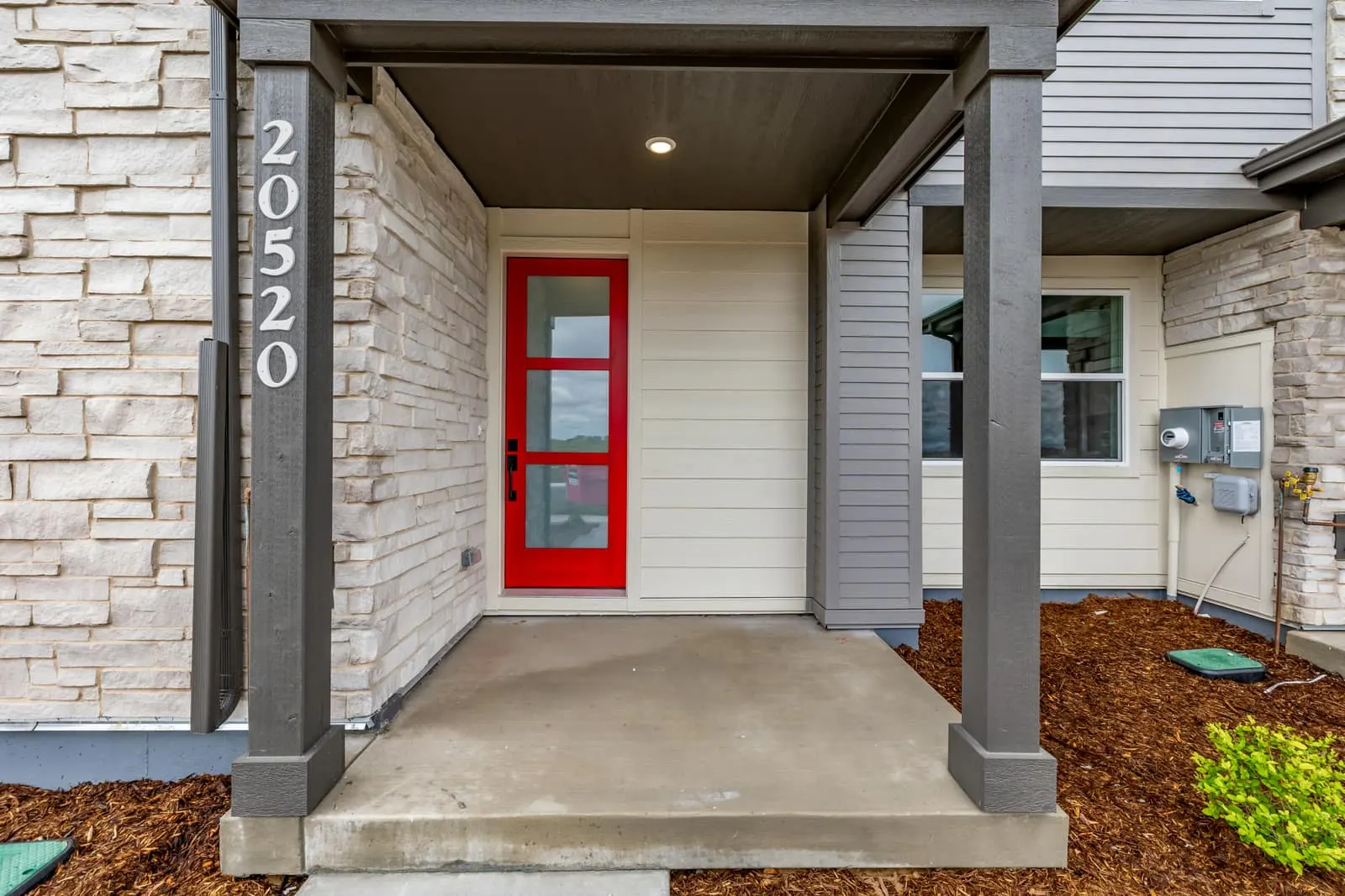Covered front entry with red door at 20520 E. 58th Ave in Painted Prairie, Aurora, Colorado