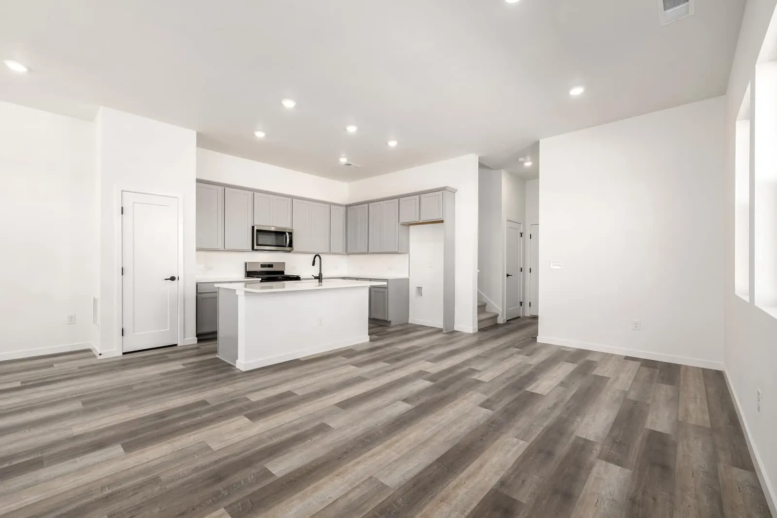 Open living room and white kitchen at 20500 E. 58th Ave in Painted Prairie, Aurora, Colorado